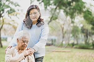 Touching Asian senior or elderly old lady woman patient on wheelchair with love, care, encourage and empathy in park