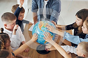 Touching the Earth globe. Group of children students in class at school with teacher