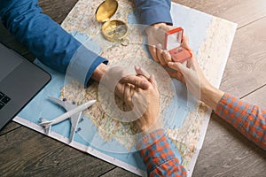 Touching moment the guy proposing at the table with the map and Ring in the box. Travel adicted young couple.