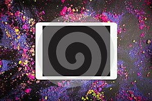 Touchpad with blank screen on colorful crumbled eyeshadows or holi colors on black background