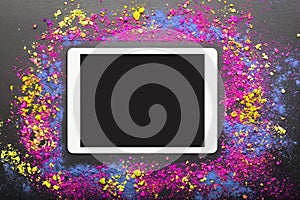 Touchpad on colorful holi powder background. Touchscreen computer on festive holi colors background.