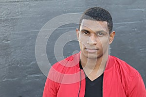 Tough African guy dressed in red and black near a dark wall