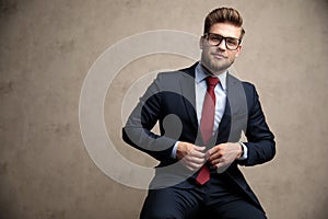 Tough businessman fixing his jacket and looking forward