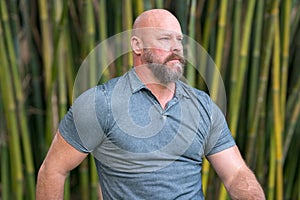Tough guy looking away from camera. Bald head with full beard