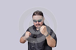 A tough looking bodyguard or security escort challenges someone to a fistfight. A man wearing shades ready to defend himself in photo