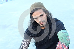 Tough looking hispanic man with long hair and tattoos