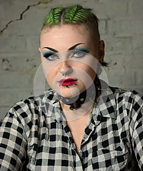 Tough looking punk girl. Facial piercings & green hair, spiked collar.