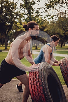 Tough muscular men flipping tires in the park
