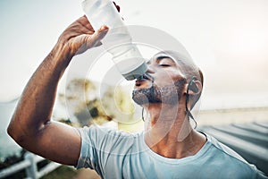 Tough times dont last. Tough people do. a sporty young man drinking water while exercising outdoors.