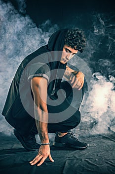 Tough young man in dark t-shirt on grey background