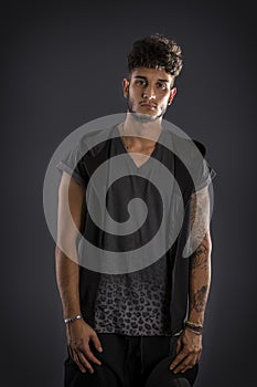 Tough young man in dark t-shirt on grey background