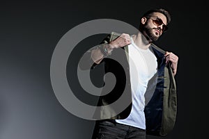 Tough young man pulling his jacket`s collar