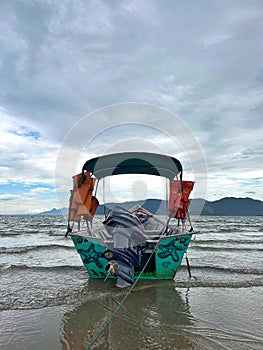 tour boat stopped on the sand of a calm beach on a cloudy day