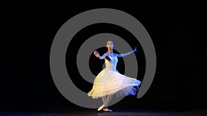 Tour lent. Graceful ballerina in elegant white dress practicing base movements in ballet dance. Concept of beauty