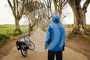 Touring bicycle set up with panniers. dark hedges in Northern Ireland. Traveler male stand by bicycle visit famous landmarks in