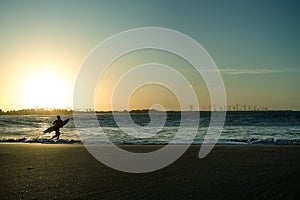 Tourinhos, Brazil, November 23, 2022. Silhouette of a surfer running into the waves with his board during sunset. In the