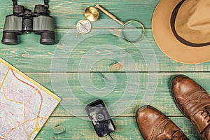 Tourism concept. Magnifying glass, compass, city map, binoculars, brown shoes, fedora hat and old film camera
