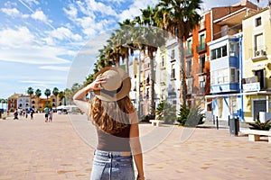 Tourism in Europe. Happy traveler girl visiting the colorful Spanish village with palm trees and beaches Villajoyosa, Alicante, photo
