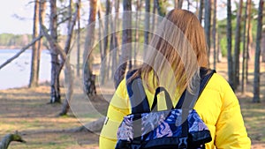 Tourism, hiking and outdoor recreation. Back view of a young sportswoman with a backpack walking in the middle of a pine