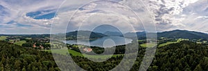 The tourism hotspot lake Tegernsee from above in a wide panoramic view at a warm and cloudy summer day.