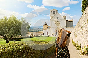 Tourism in Italy. Back view of beautiful girl enjoying view of the Basilica of Saint Francis of Assisi in Umbria, Italy