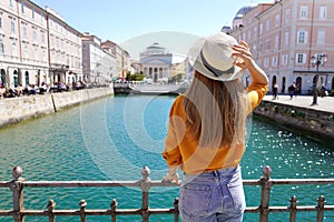 Tourism in Italy. Back view of pretty girl holding hat in Trieste, Italy. Beautiful young woman visiting Europe