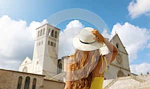 Tourism in Italy. Back view of tourist woman in Assisi looks at Basilica of Saint Francis, Umbria, Italy