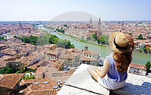 Tourism in Italy. Beautiful young woman sitting on wall enjoying stunning view of Verona, Italy