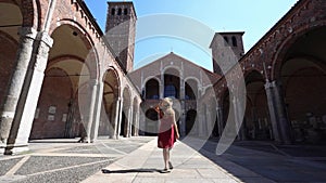 Tourism in Italy. Full length of young woman walking towards the St. Ambrose Basilica in Milan, Italy. Slow motion.