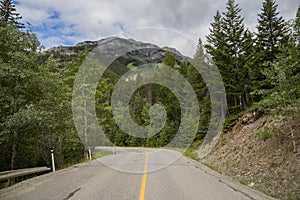 Tourism in the mountains - a road in the forest between the mountains. Great view, summer vacation, Banff, Alberta, Canada