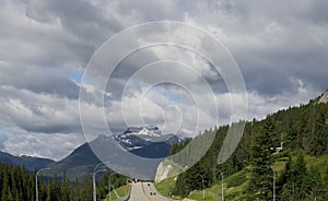 Tourism in the mountains - a road in the forest between the mountains. Great view, summer vacation, Banff, Alberta, Canada