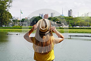 Tourism in Sao Paulo, Brazil. Back view of traveler girl enjoying skyline of Sao Paulo metropolis from Ibirapuera Park, Brazil photo