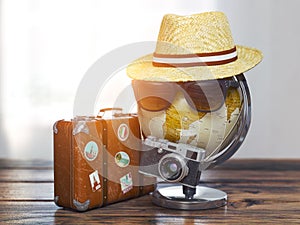 Tourism and travel concept. Globe with summer hat, sunglasses photo camera and vintage suitcase. ready to trip
