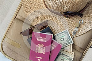Tourism travel concept. Suitcase with female hat, sunglasses, spanish passports, dollars and padlock