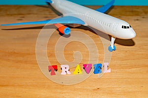 Tourism and travel concept, toy airplane and color letters on wooden background