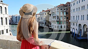 Tourism in Venice, Italy. Back view of young woman on Rialto Bridge looking at the Grand Canal in Venice, Italy. Slow motion.