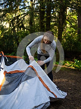 Tourism. The woman lays out the tent. Rest, day off. Pedestrian road. In the distance is a forest. A bright sunny day. Good mood.