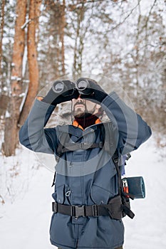 Tourist in Anorak With Backpack Using Binoculars