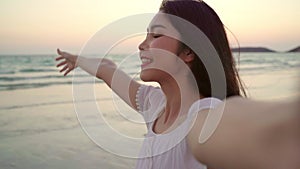 Tourist Asian woman selfie on beach, young beautiful female happy smiling using mobile phone taking selfie on beach near sea when