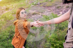 Tourist asian woman getting help to friend climb a rock,Helping hands,Overcoming obstacle concept