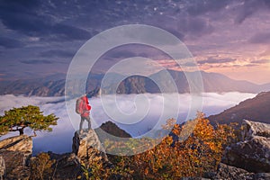 tourist with backpack admiring landscape in Autumn In the morning, a sea of mist flows through the river in the valley In the