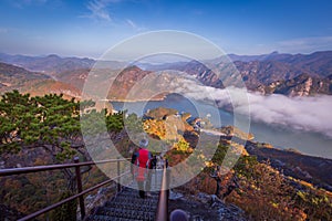 tourist with backpack admiring landscape in Autumn In the morning, a sea of mist flows through the river in the valley In the