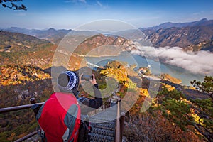 tourist with backpack admiring landscape in Autumn In the morning, a sea of mist flows through the river in the valley In the
