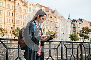 A tourist with a backpack in front of a beautiful old architecture in Prague in the Czech Republic. She looks at the map