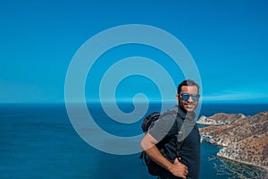 Tourist with backpack standing on a rock at the top of the mountain and admiring the view near the beach of Santa Marta, Colombia