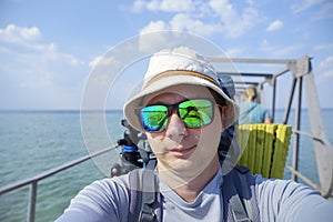 Tourist with a backpack takes a selfie on the camera at the sea pier