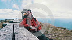 Tourist with Backpack on Top of Mountain Sat Down to Rest at an Old Wooden Table