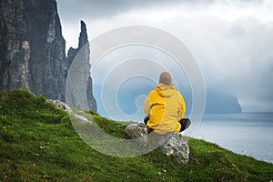 Tourist with backpack in yellow jacket looks at Witches Finger cliffs