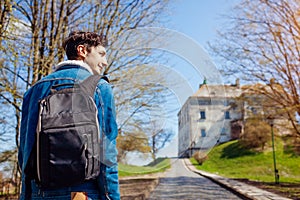 Tourist backpacker visiting Olesko Castle in autumn. Trip to Western Ukraine. Traveler enjoys fall landscape