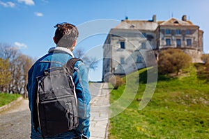 Tourist backpacker visiting Olesko Castle in spring. Trip to Western Ukraine. Traveler enjoys landscape